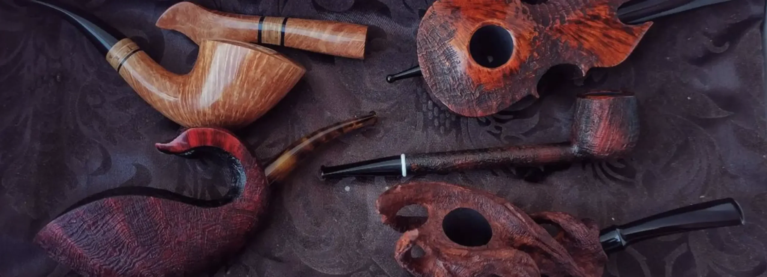 Close-up of a collection of handmade tobacco pipes, crafted by Dominik Demon.